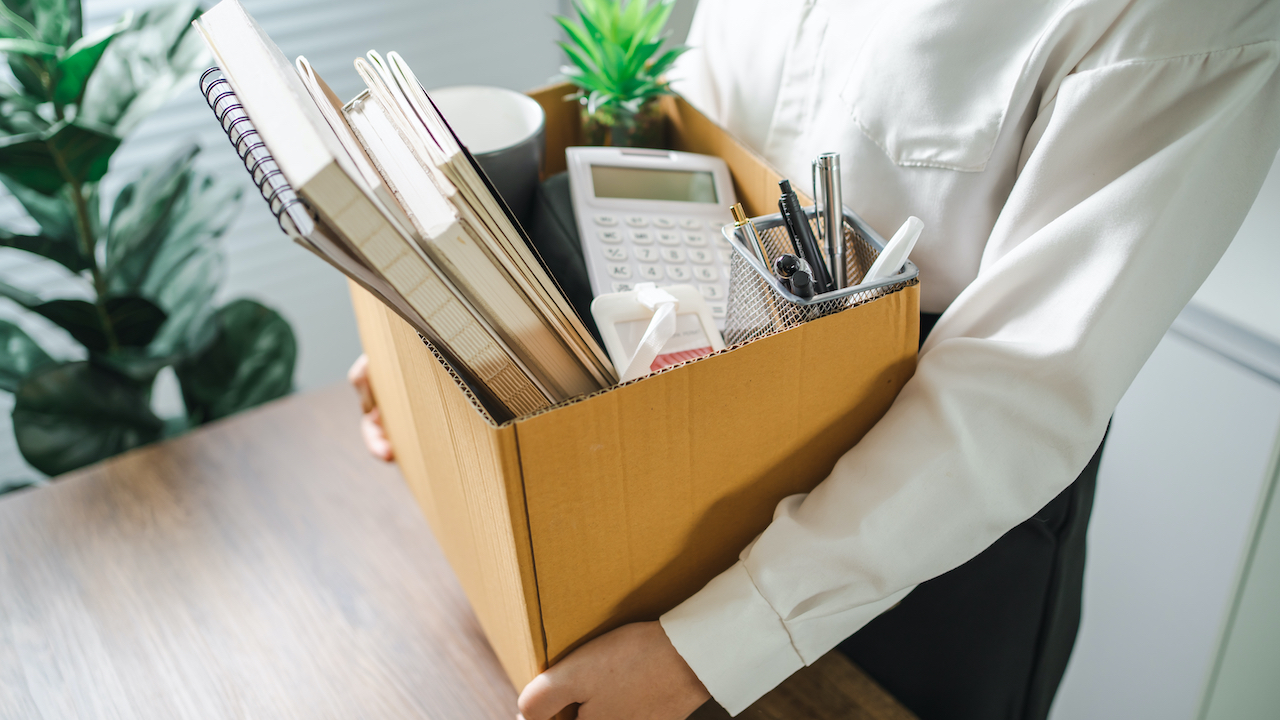 Frau mit Büro-Utensilien im Pappkarton