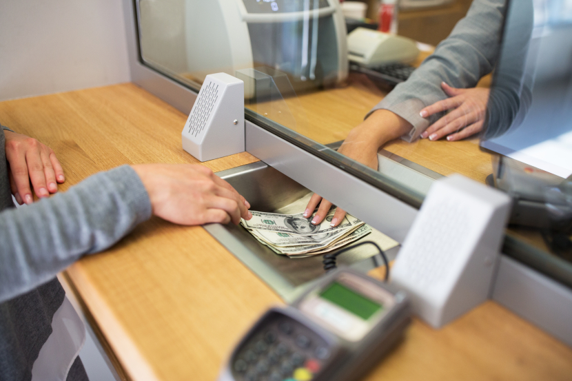 An einem Bankschalter wird Geld druchgereicht