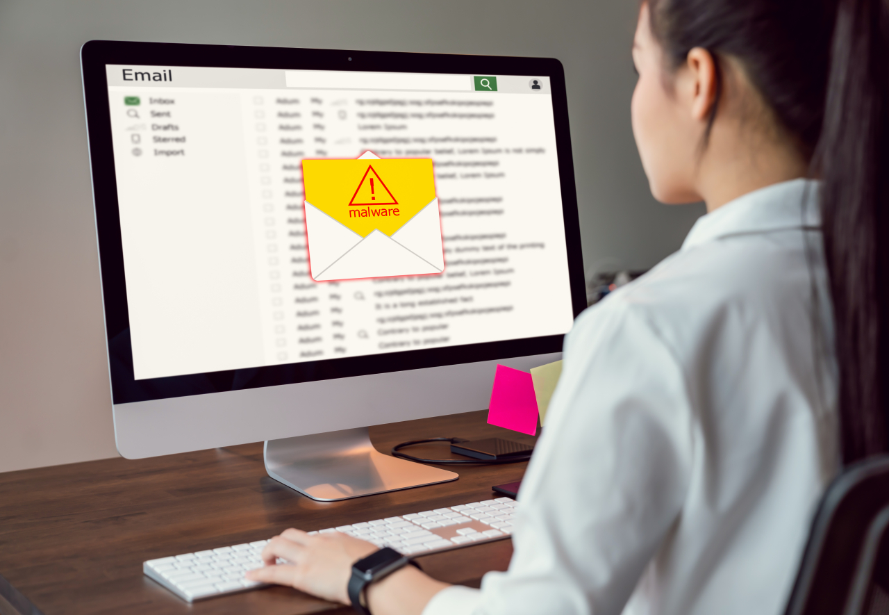 Eine Frau sitzt vor einem Rechner, auf dem Bildschirm erscheint eine gelbe Warnung