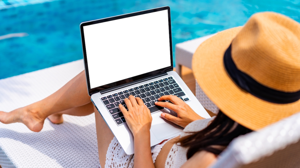 Frau mit Laptop am Pool