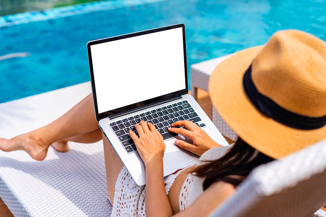 Frau mit Laptop am Pool