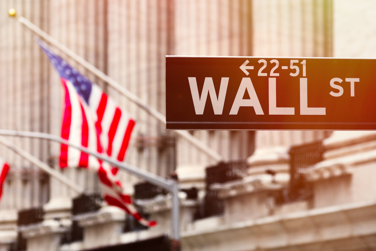 Bild vom Wall Street Schild mit einer US Flagge im Hintergrund