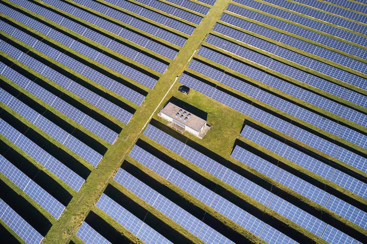 Schnurgerade Reihen von Kollektoren eines Solarparks aus der Luft
