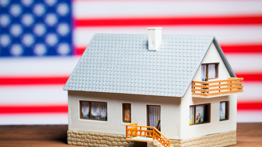 Modell eines Einfamilienhauses vor einer US-Flagge