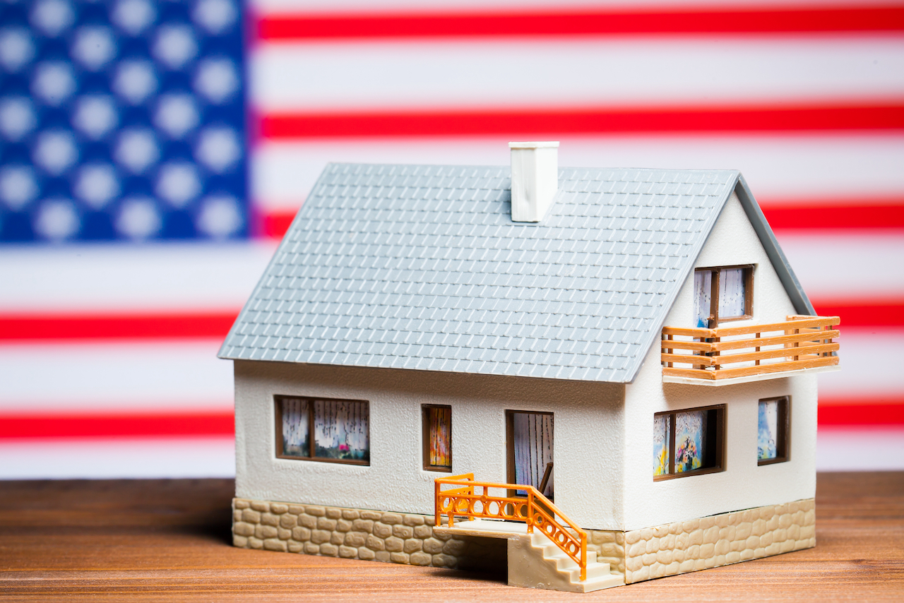 Modell eines Einfamilienhauses vor einer US-Flagge