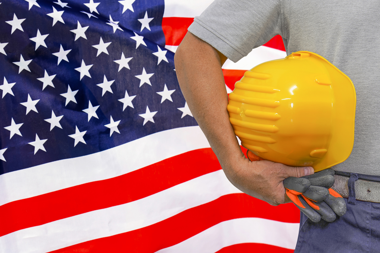Bauarbeiter mit Helm vor US-Flagge