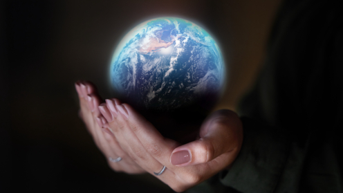 Frauenhand hält einen Globus vor schwarzem Hintergrund