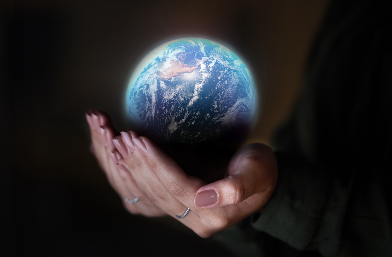 Frauenhand hält einen Globus vor schwarzem Hintergrund