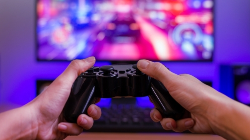 Joypad in der Hand. Spielkonzept. Computerdisplay mit Rennspiel und RGB-Licht im Hintergrund.