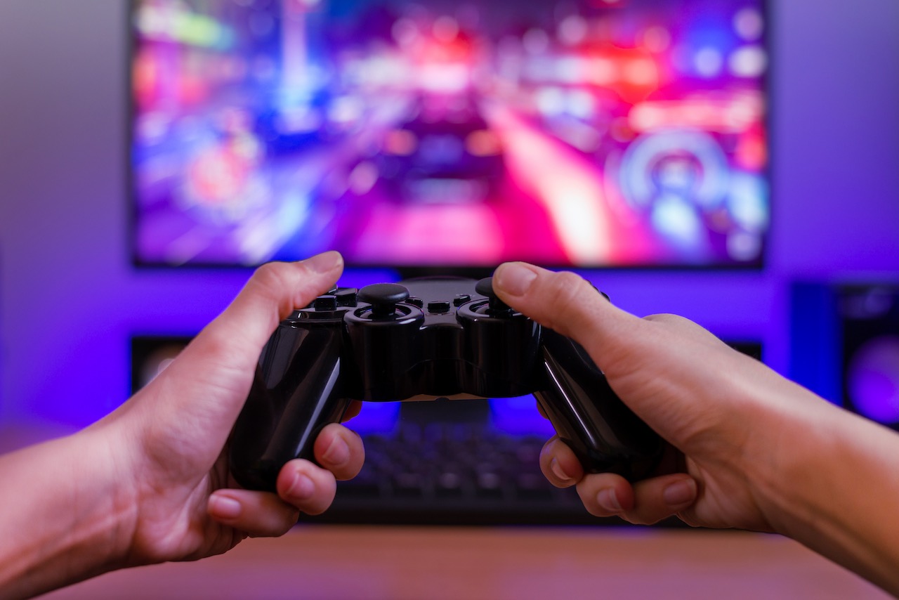 Joypad in der Hand. Spielkonzept. Computerdisplay mit Rennspiel und RGB-Licht im Hintergrund.