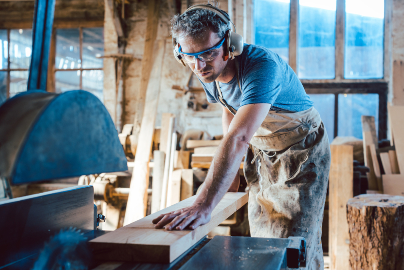 Zimmermann arbeitet mit der Kreissäge an Holz