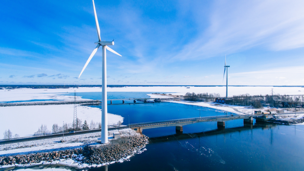 Luftaufnahme von Windmühlen mit blau gefrorenem Fluss im schneebedeckten Winter Finnland.