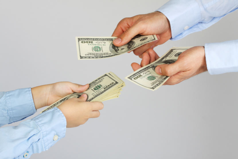 Männerhände geben den Jungenhänden Geld in Form von Hundert-Dollar-Scheinen. Geschäftsleute geben Geschäftsleuten Geld. Vater und Sohn.