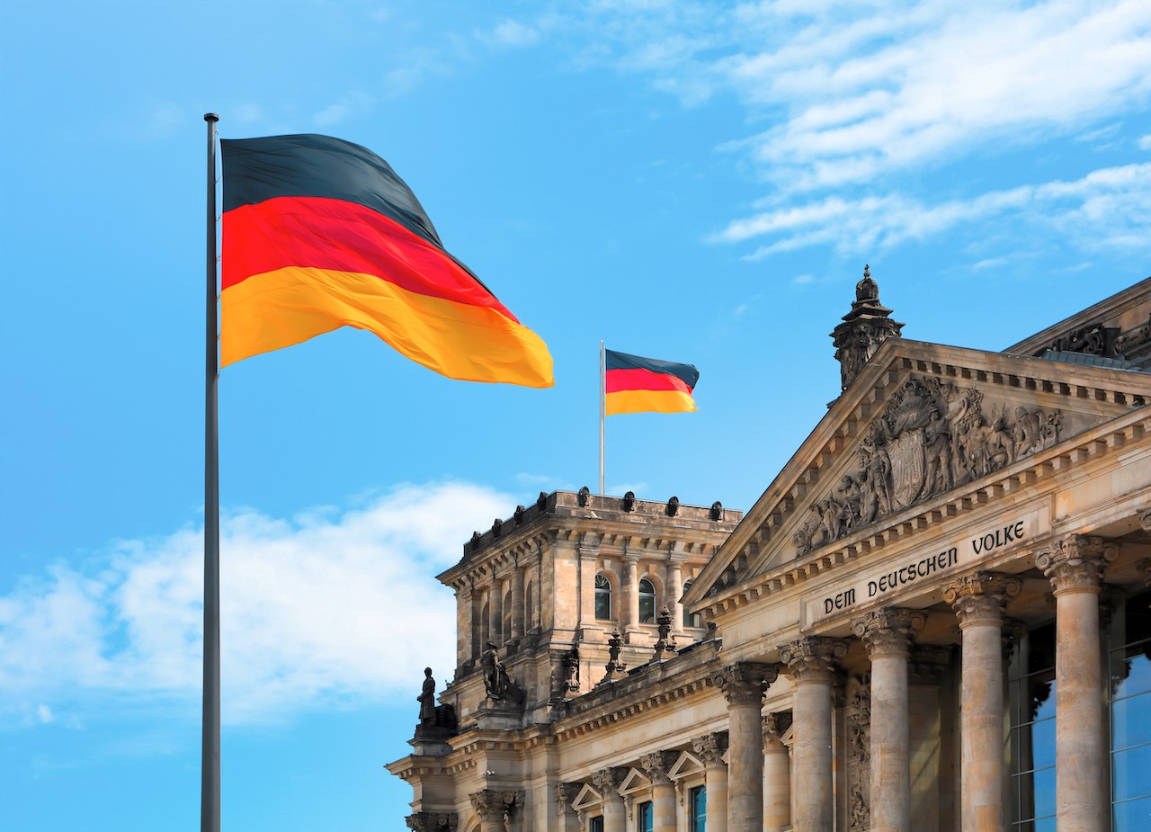 Deutschland-Fahne vor der Kuppel des Reichstags in Berlin