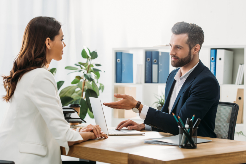 schöner Berater im Anzug im Gespräch mit schönem Investor im Büro