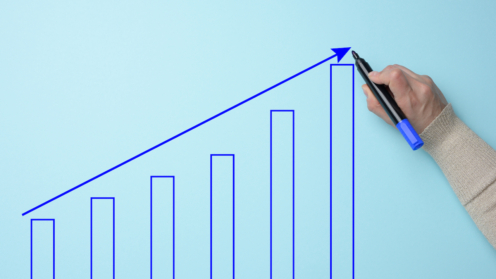 Graph with growing indicators and a female hand with a marker on a blue background. The concept of successful sales in business, inflation and rising prices