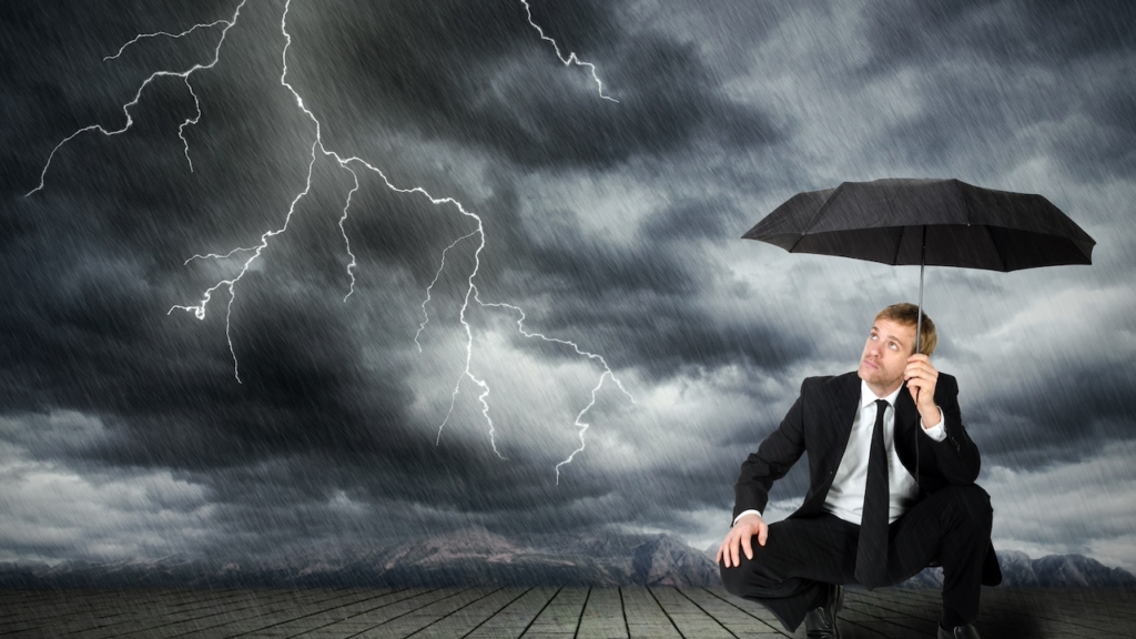 Mann im Anzug und Regenschirm sucht Schutz vor Unwetter