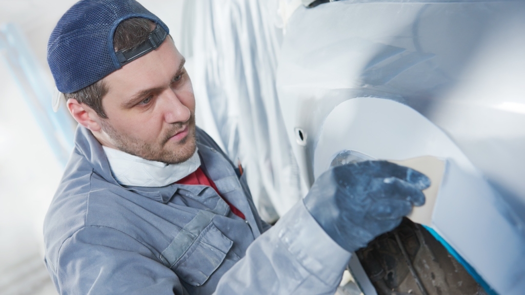 Autoreparator verputzt Karosseriehaube