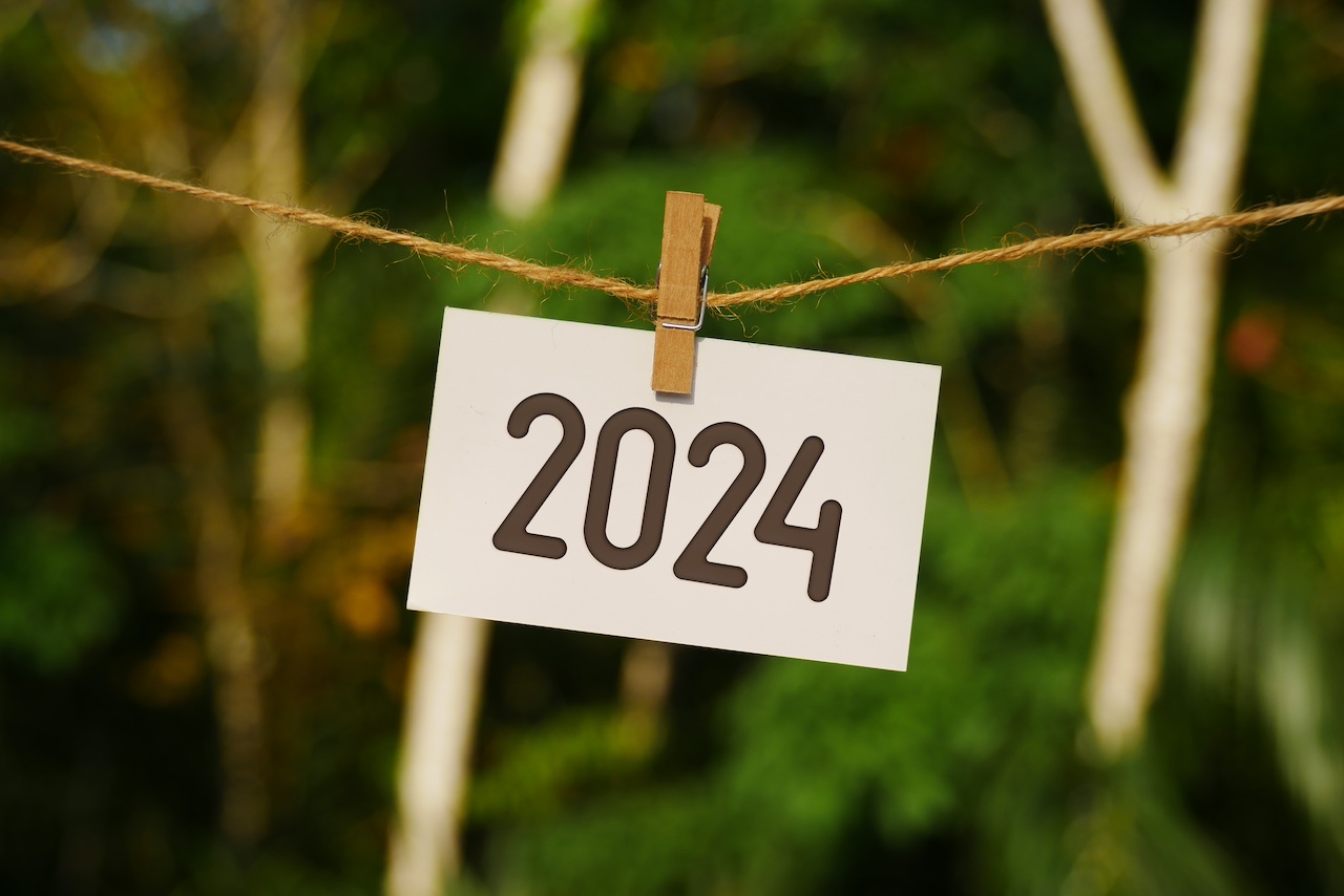 2024 auf Papier, das an einem Juteseil hängt. Auf Wiedersehen 2023 hallo Frohes Neues Jahr 2024.