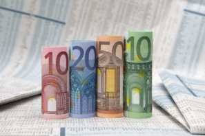 Gerollte Euro-Scheine vor einer Finanzzeitung