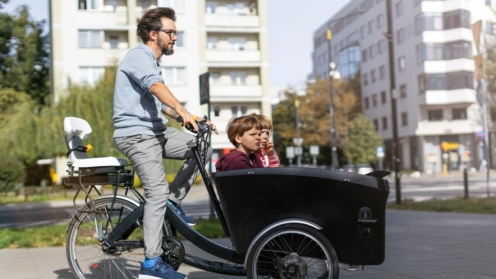 Vater und Kinder bei einer Fahrt mit dem Lastenrad in einer Stadt