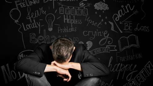 ein Mann in Depressionen schließt mit der Hand auf dem Hintergrund einer gezeichneten Tafel mit Problemen