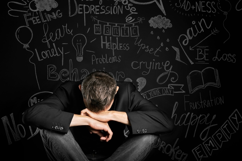 ein Mann in Depressionen schließt mit der Hand auf dem Hintergrund einer gezeichneten Tafel mit Problemen