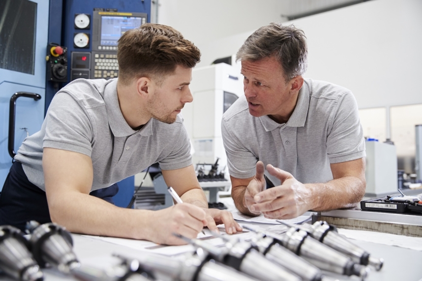 Ingenieur zeigt Lehrling an,wie man CAD-Zeichnungen misst