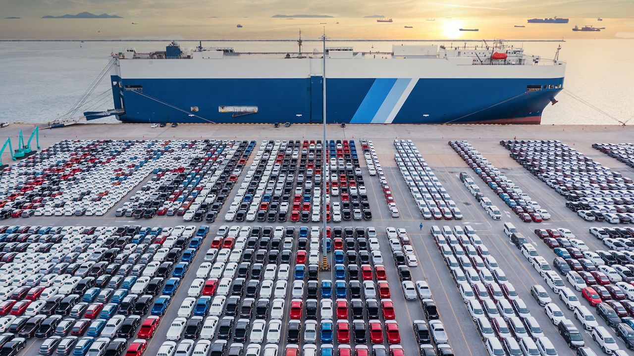 Luftbild-Fahrzeugträgerschiff,das Auto für den weltweiten Versand belädt,Großer RoRo-Fahrzeugtransporter (Roll on / off),Neuwagen im Hafen für den Importexport in die ganze Welt aufgereiht.