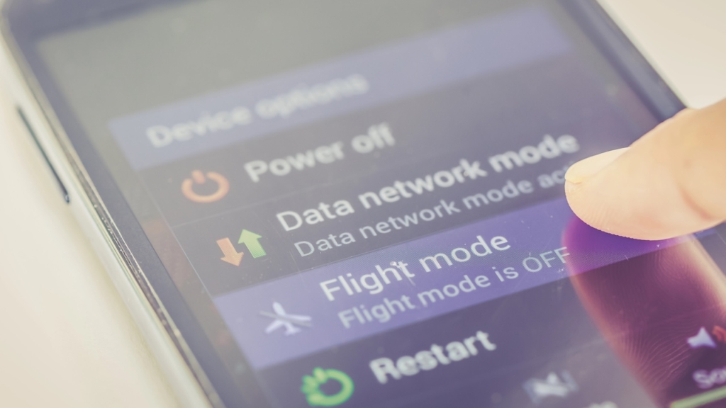 Nahaufnahme des Fingers, der die Flugmodus-Taste auf dem Smartphone drückt