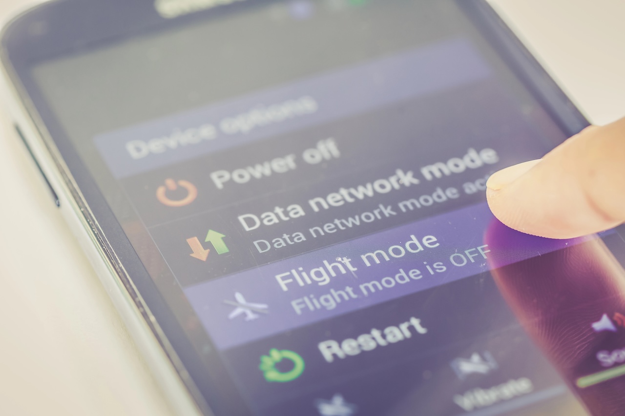 Nahaufnahme des Fingers, der die Flugmodus-Taste auf dem Smartphone drückt