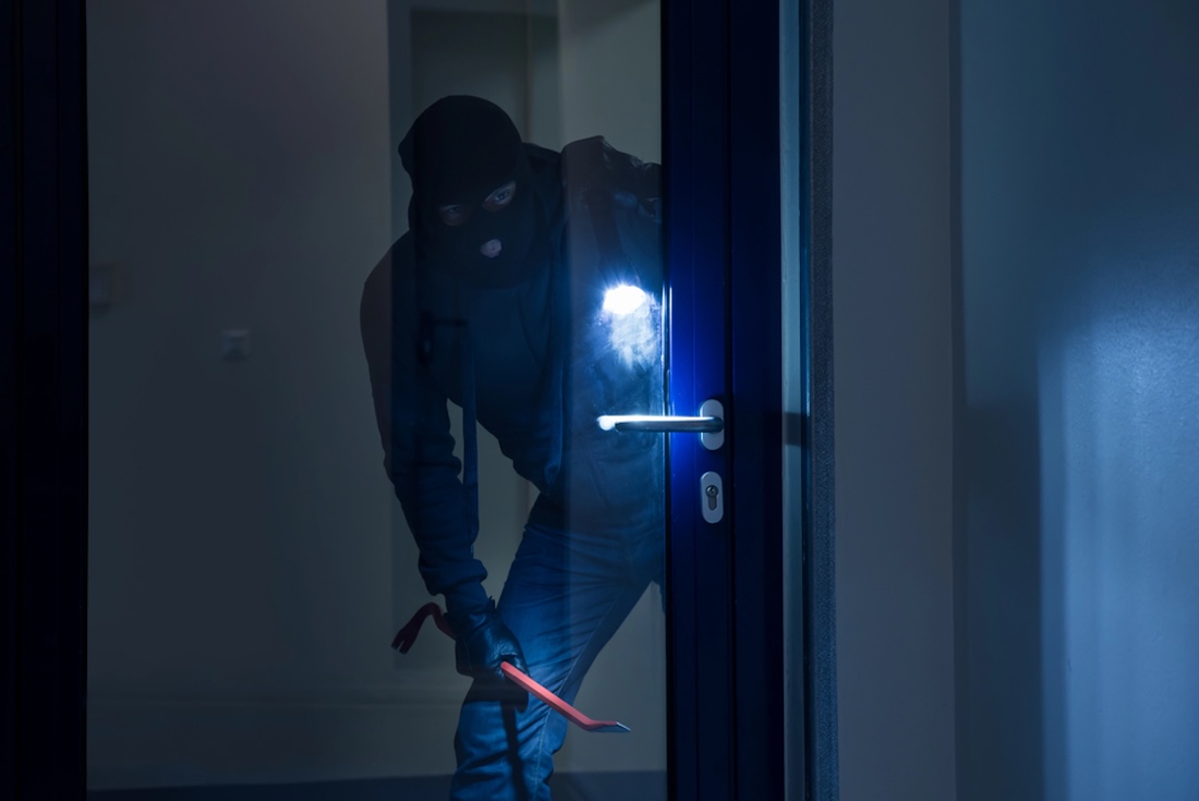 Einbruch bei Nacht, Einbrecher vor einer Glastür, Hausratversicherung, Versicherung
