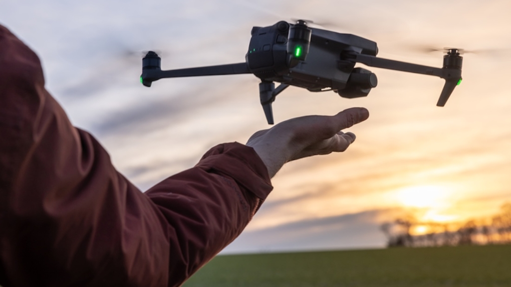 Ein Arm befindet sich unter einer Drohne, die von der Handfläche aus startet und landet. Erfahrene Drohnenpiloten starten und fangen ihre Drohnen oft mit der Hand. , Recht, Steuern, Versicherungen