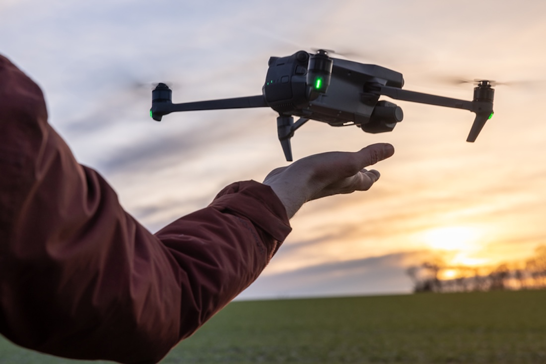 Ein Arm befindet sich unter einer Drohne, die von der Handfläche aus startet und landet. Erfahrene Drohnenpiloten starten und fangen ihre Drohnen oft mit der Hand. , Recht, Steuern, Versicherungen