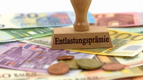 Stempel mit dem Aufdruck "Entlastungsprämie" auf Geldscheinen und Münzen