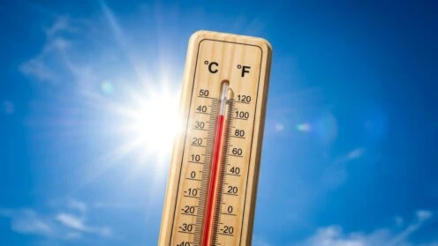 Thermometer mit 40 Grad vor blauem Himmel mit Sonne