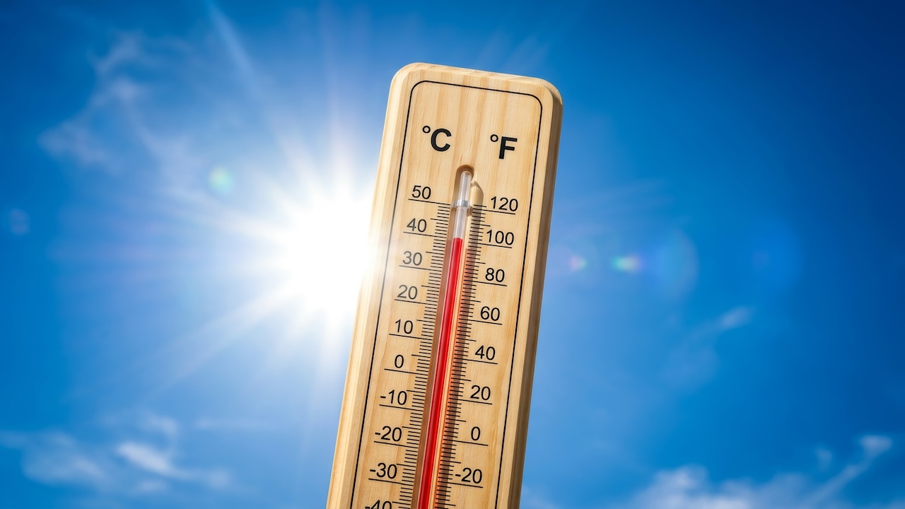 Thermometer mit 40 Grad vor blauem Himmel mit Sonne