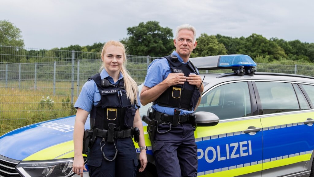Polizeibeamte vor ihrem Dienstwagen