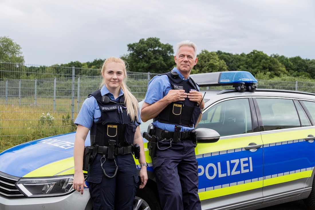 Polizeibeamte vor ihrem Dienstwagen
