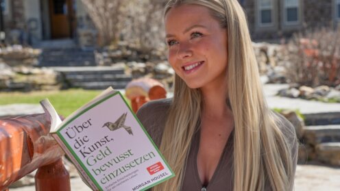 Celine Nadolny mit dem Buch "Über die Kunst, Geld bewusst einzusetzen" von Morgan Housel in der Hand.