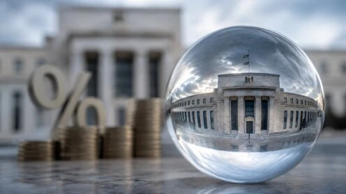 Glaskugel mit Spiegelung eines repräsentativen Notenbankgebäudes vor Münzstapeln und einem Prozentzeichen als Symbol für Geldpolitik, Zinsen und Finanzmärkte.