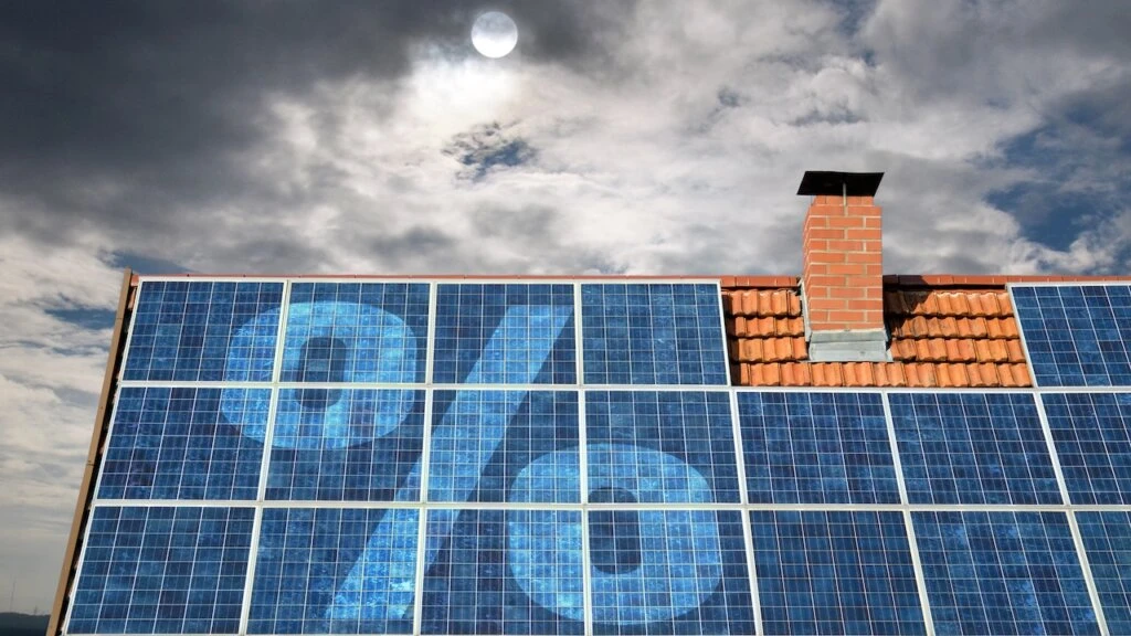 Photovoltaikmodule auf dem Dach eines Wohnhauses vor teils bewölktem Himmel, überlagert von einem Prozent-Symbol