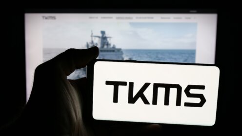 TKMS-Logo auf Smartphone for Computerbildschirm mit Marineschiff