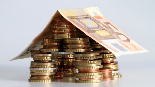 Euro-Münzen und ein 50-Euro-Schein sind zu einem Haus arrangiert und symbolisieren Wohnkosten sowie das Wohngeld in Deutschland.
