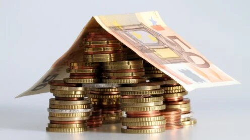 Euro-Münzen und ein 50-Euro-Schein sind zu einem Haus arrangiert und symbolisieren Wohnkosten sowie das Wohngeld in Deutschland.