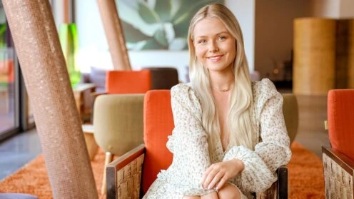 Celine Nadolny sitzt in einem Raum mit Retro-Stühlen und zwei schrägen Säulen