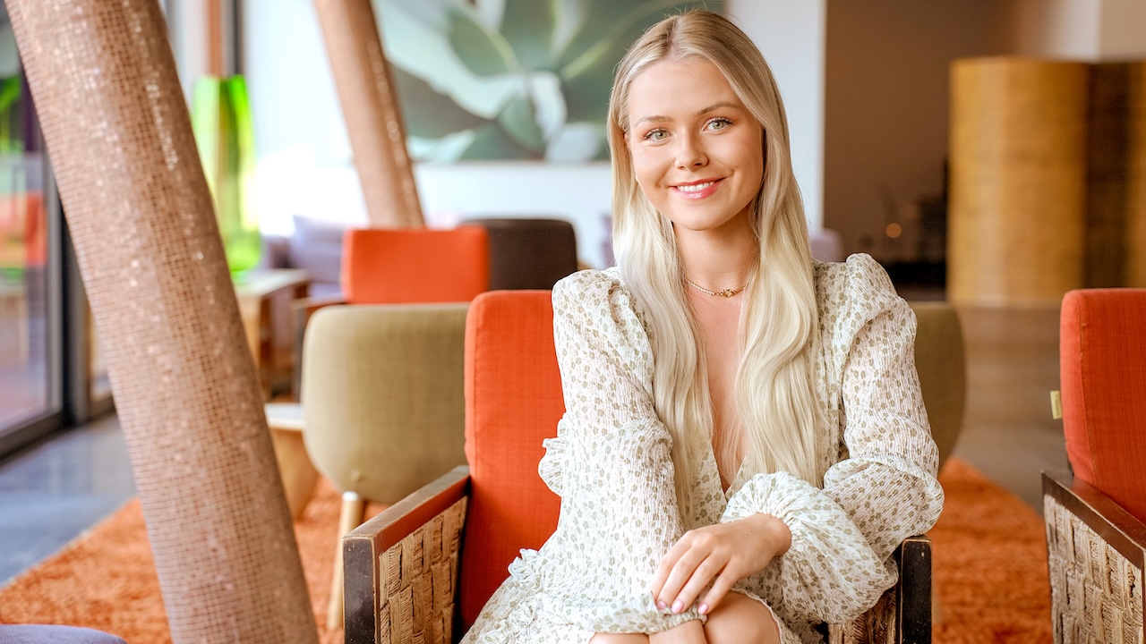 Celine Nadolny sitzt in einem Raum mit Retro-Stühlen und zwei schrägen Säulen