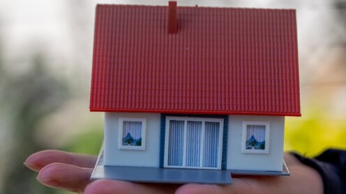 Jemand hält ein Modellhaus auf seiner Hand