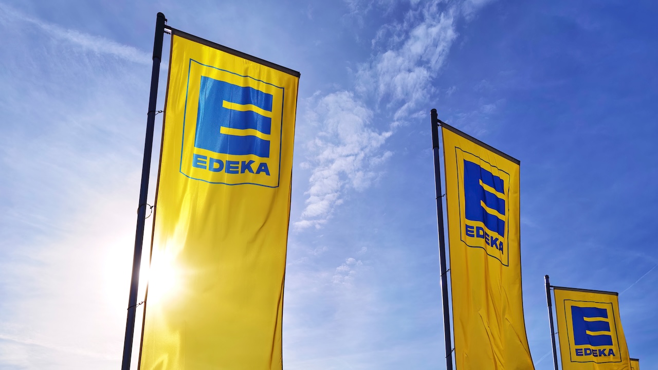 Gelbe Edeka-Fahnen wehen vor blauem Himmel.