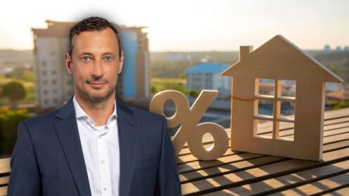 Marco Schöfl von Qualitypool vor einem Holzhaus und einem Prozentzeichen als Symbol für Bauzinsen und Immobilienfinanzierung.